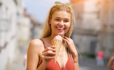 bir yaz elbise güneşli bir kız dondurma yiyor ve t etrafında yürüyor