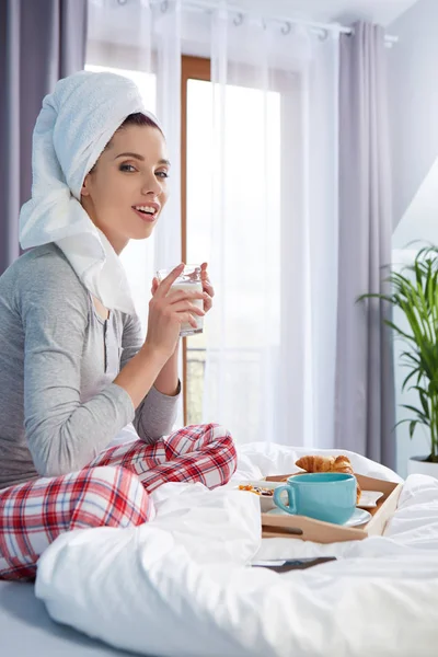 Menina com uma toalha na cabeça tomando café da manhã na cama — Fotografia de Stock