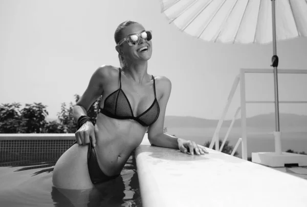 Femme saine souriante dans la piscine dans les lunettes de soleil. BW — Photo