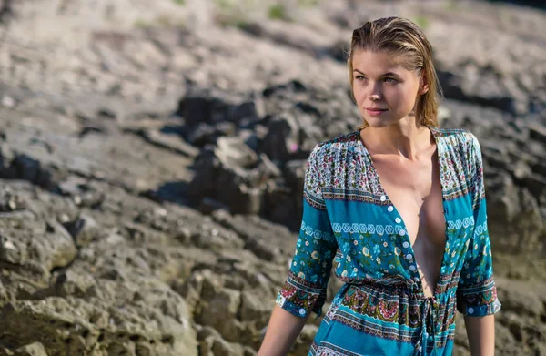 Mujer de moda posando en una playa con rocas en un vestido largo —  Fotos de Stock