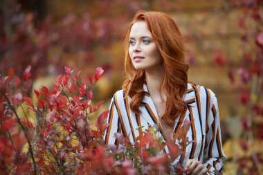 Gülümseyen kızıl saçlı açık havada güneş, moda çekimi tarafından arkadan aydınlatmalı. Yakın çekim