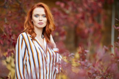 Gülümseyen kızıl saçlı açık havada güneş, moda çekimi tarafından arkadan aydınlatmalı. Yakın çekim