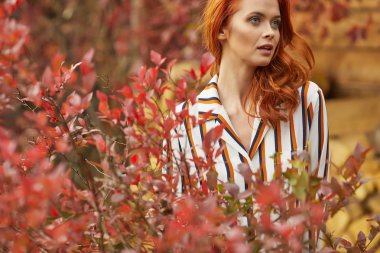 Gülümseyen kızıl saçlı açık havada güneş, moda çekimi tarafından arkadan aydınlatmalı. Yakın çekim