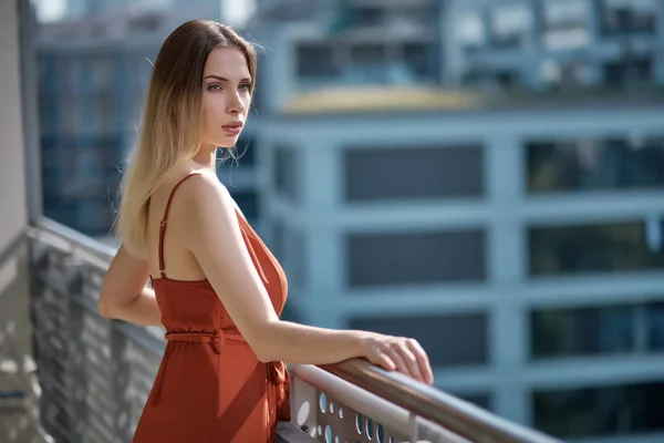 Elegante donna sexy in abito estivo rosso in piedi sulla terrazza in ci — Foto Stock