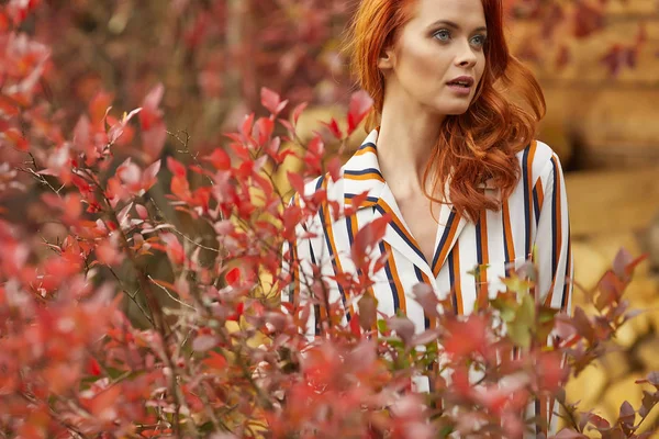 Smiling redhead outdoors backlit by sun, fashion shoot. Close up