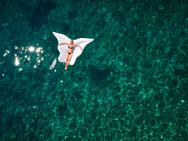 Top down view of a beautiful woman in a white bikini who is floa