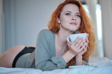 Güzel kadın evde yatağında oturup bir kahve içme