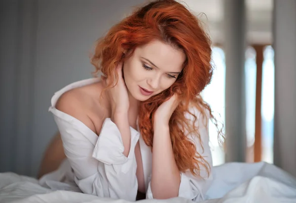 Erkek gömleği içinde kızıl saçlı kız yatakta yatıyor — Stok fotoğraf