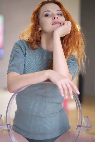 Sandalyede oturan genç kızıl saçlı kadın — Stok fotoğraf