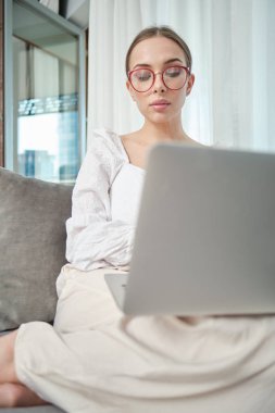 Evde dizüstü bilgisayar üzerinde çalışan güzel genç gülümseyen kadın