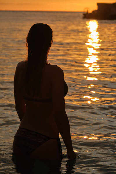 Silhouette of a woman in the sea against the backdrop of the set