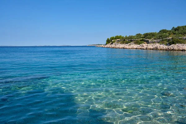 Cristalino azul claro mar Adriático verde e uma praia rochosa no i — Fotografia de Stock