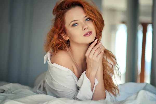 A woman in a man's shirt is lying on the bed — Stock Photo, Image