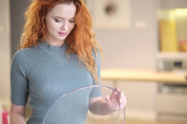 Kameraya bakıp gülümseyen komik kızıl saçlı kızın yakın portresi.