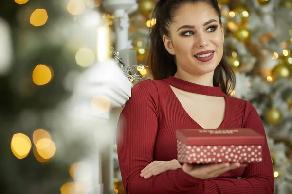 Sorrindo jovem com caixa de presente de Natal perto de natal tr — Fotografia de Stock