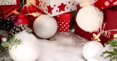 Kırmızı Noel hediye kutusu. Arkaplanda kar yağıyor ve renkli bir çam ağacı var.