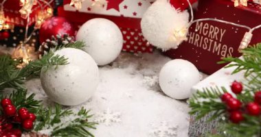 Kırmızı Noel hediye kutusu. Arkaplanda kar yağıyor ve renkli bir çam ağacı var.