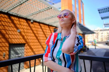 Renkli bir tişörtle şehirde yürüyen bir kız.