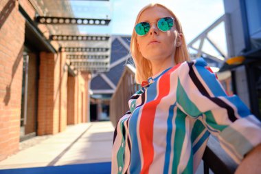 Renkli bir tişörtle şehirde yürüyen bir kız.