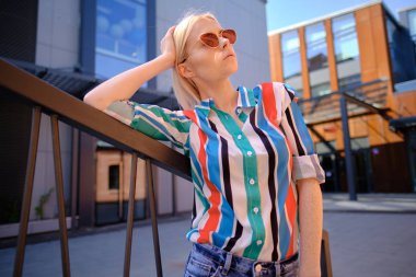 Renkli bir tişörtle şehirde yürüyen bir kız.