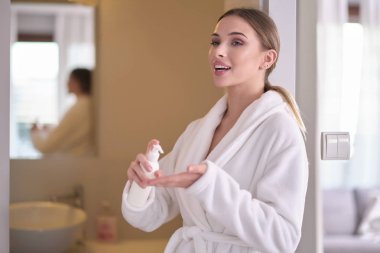 Kusursuz ciltli genç bir kadın, nemlendirici krem sürüyor.