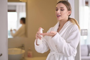 Kusursuz ciltli genç bir kadın, nemlendirici krem sürüyor.