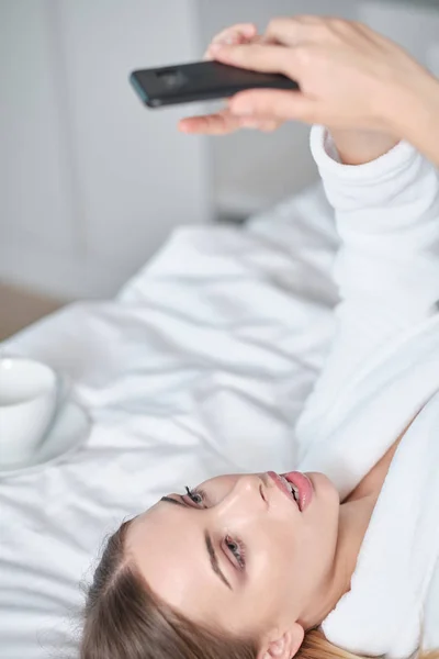 Schöne junge Frau im Bademantel mit Ruhe auf bequemen Bett — Stockfoto