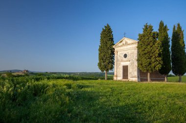 A vertical shot of the famous historic Chapel Vitaleta in the middle of a field in Italy