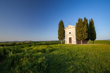 A vertical shot of the famous historic Chapel Vitaleta in the middle of a field in Italy