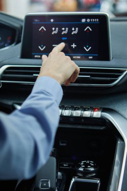 Modern bir elektrikli arabanın klimasını şoför kontrol ediyor.