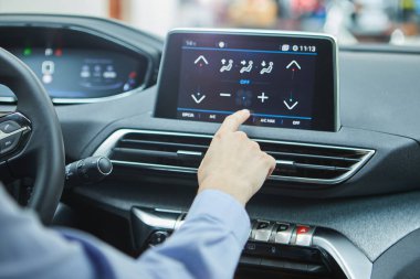 Modern bir elektrikli arabanın klimasını şoför kontrol ediyor.