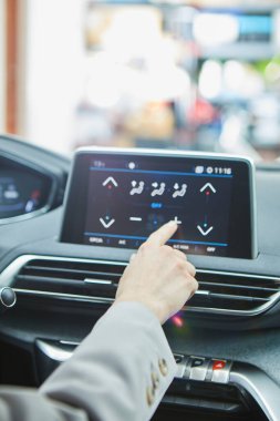 Modern bir elektrikli arabanın klimasını şoför kontrol ediyor.