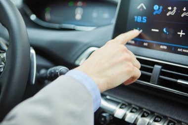 Modern bir elektrikli arabanın klimasını şoför kontrol ediyor.