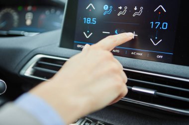 Modern bir elektrikli arabanın klimasını şoför kontrol ediyor.