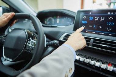 Modern bir elektrikli arabanın klimasını şoför kontrol ediyor.