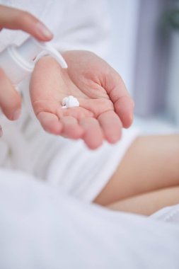 Genç bir kadın evde el kremi sürüyor, yakın plan.