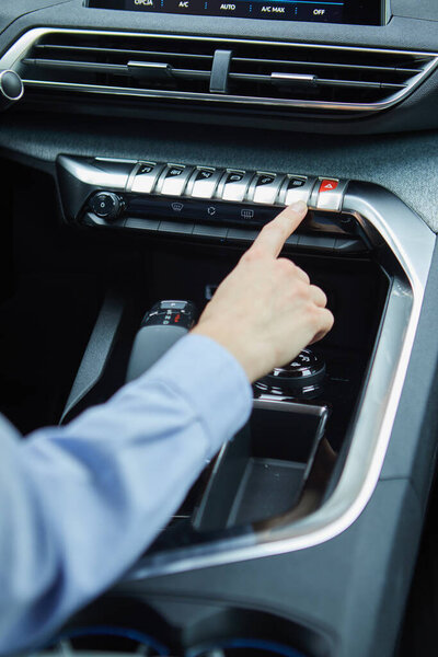водитель управляет кондиционером в современном электромобиле
