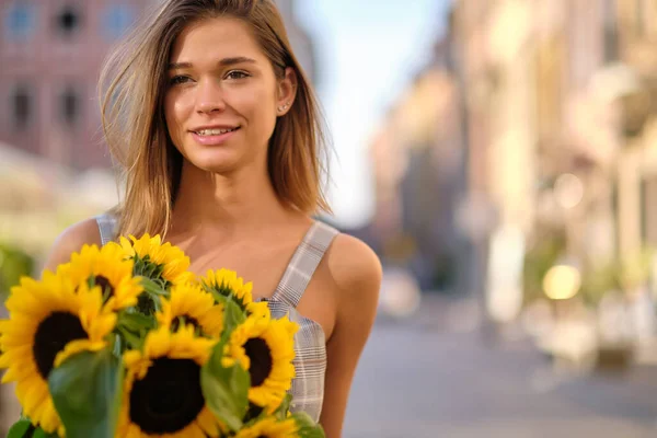 女人正在老城区散步 他手里拿着一束秋天的向日葵 — 图库照片