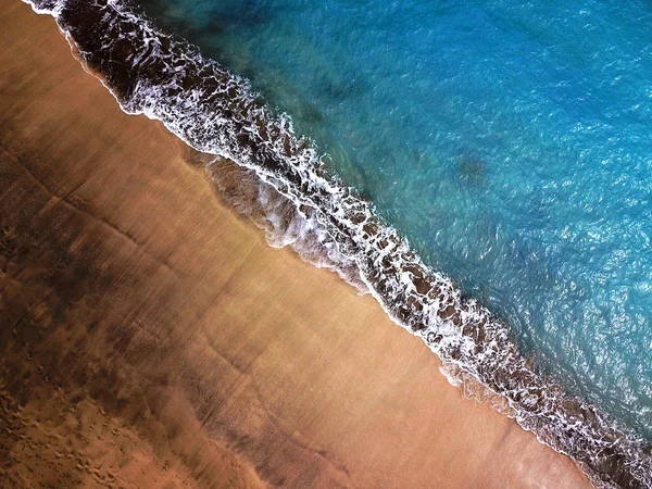 Top view of a deserted beach. Coast of the island of Tenerife, Canary Islands, Spain. Aerial drone footage of sea waves reaching shore.