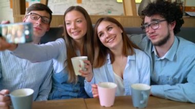 Gülümseyen arkadaşlar bir kafede oturup, iletişim iyi eğlenceler ve selfie yapmak