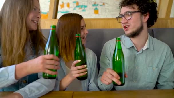 Drie vrienden zitten in een café, water of bier drinken en veel plezier bij het communiceren — Stockvideo