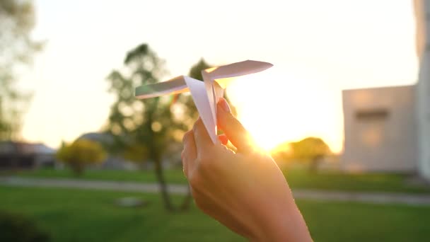 La mano lancia l'aeroplano di carta contro sfondo di tramonto. Rallentatore — Video Stock