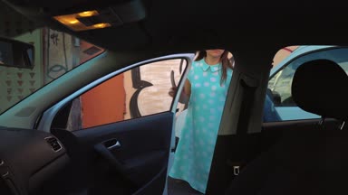 Kadın araba koltuğunda bir ceket koymak ve motoru çalıştırmayı planlayan şoför koltuğunda oturur