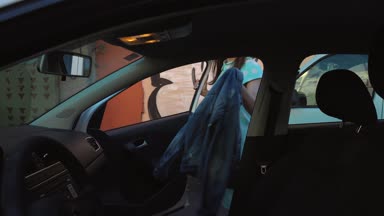Kadın araba koltuğunda bir ceket koymak ve motoru çalıştırmayı planlayan şoför koltuğunda oturur