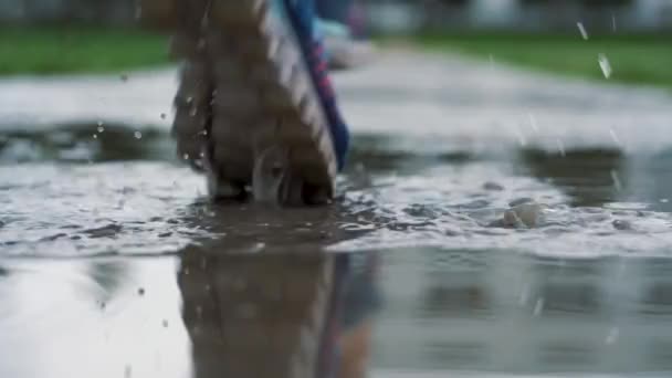在运动鞋上关闭赛跑者的腿的射击。女子运动男子在公园户外慢跑, 步入泥泞的水坑. — 图库视频影像