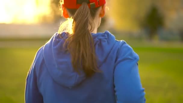 Mulher corre pelo estádio ao pôr-do-sol, vista para trás. Movimento lento — Vídeo de Stock