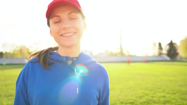 Retrato de una chica sonriente y deportiva en un estadio al atardecer — Vídeo de stock