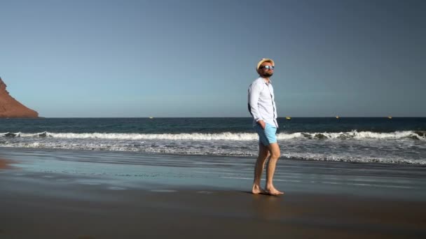 Щаслива людина прогулянки уздовж пляжу океану на заході. Концепція безтурботним сучасного життя. Тенеріфе, канарському острови, Іспанія. Повільний рух — стокове відео