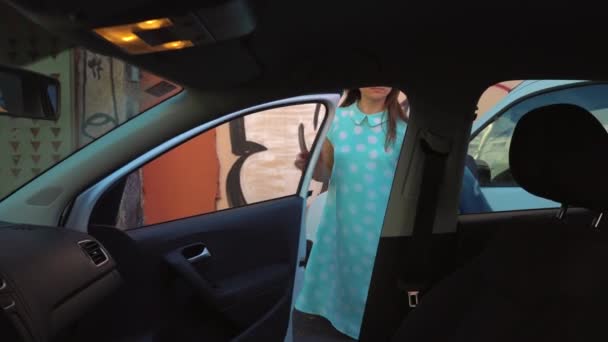 Femme a mis une veste sur le siège auto et s'assied sur le siège du conducteur, dans l'intention de démarrer le moteur — Video