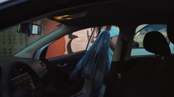 Mujer poner una chaqueta en el asiento del coche y se sienta en el asiento del conductor, con la intención de arrancar el motor — Vídeo de stock